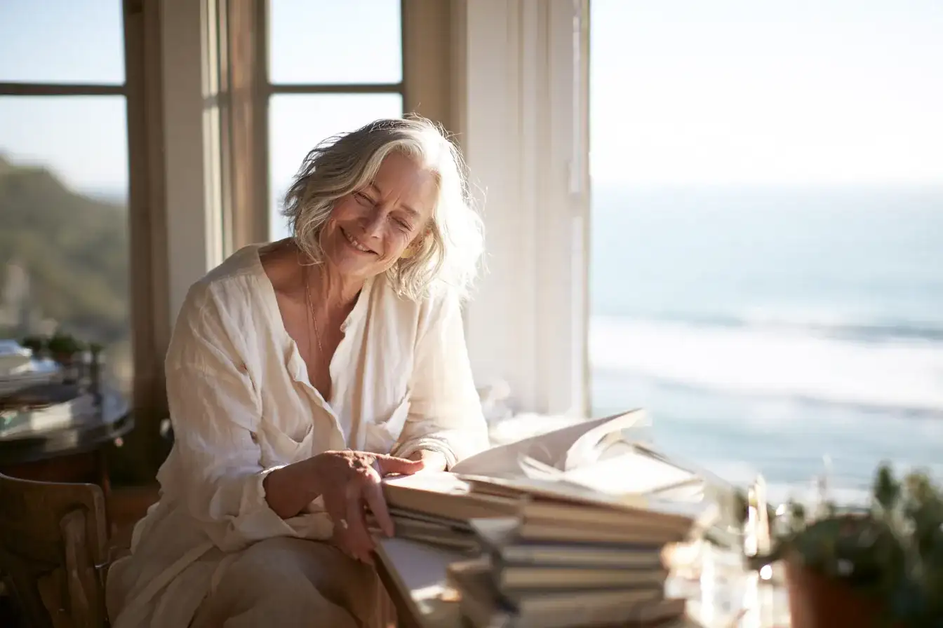 A clinician in her fifties reading at a sunlit desk