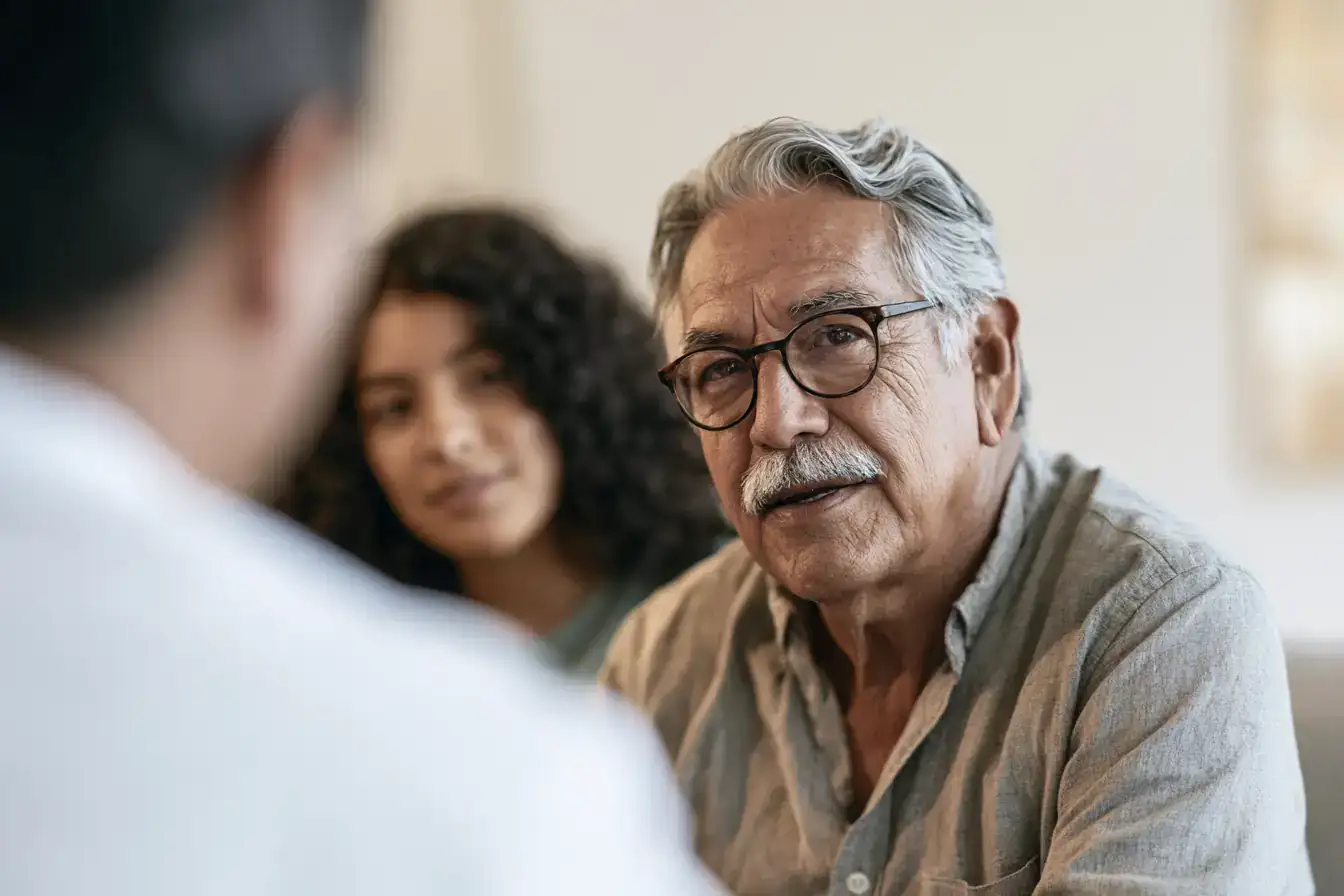 A Latino man in his seventies and his granddaughter nodding along while a clinician explains