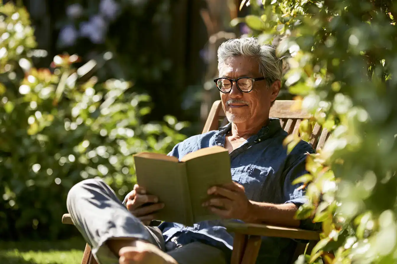 An Asian man in his late sixties filling a bird feeder in the garden