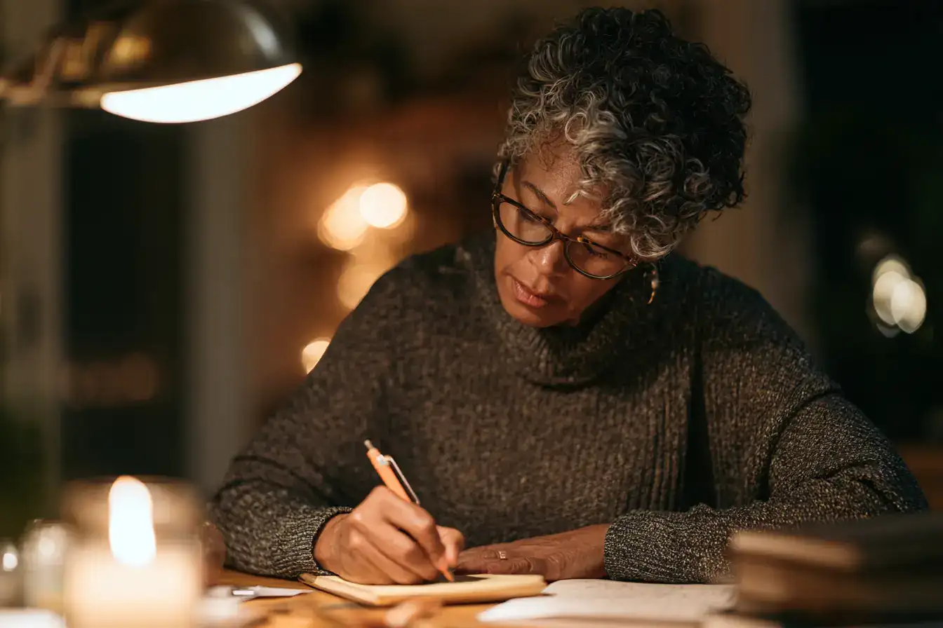 A Black woman in her fifties writing questions on a notepad the night before