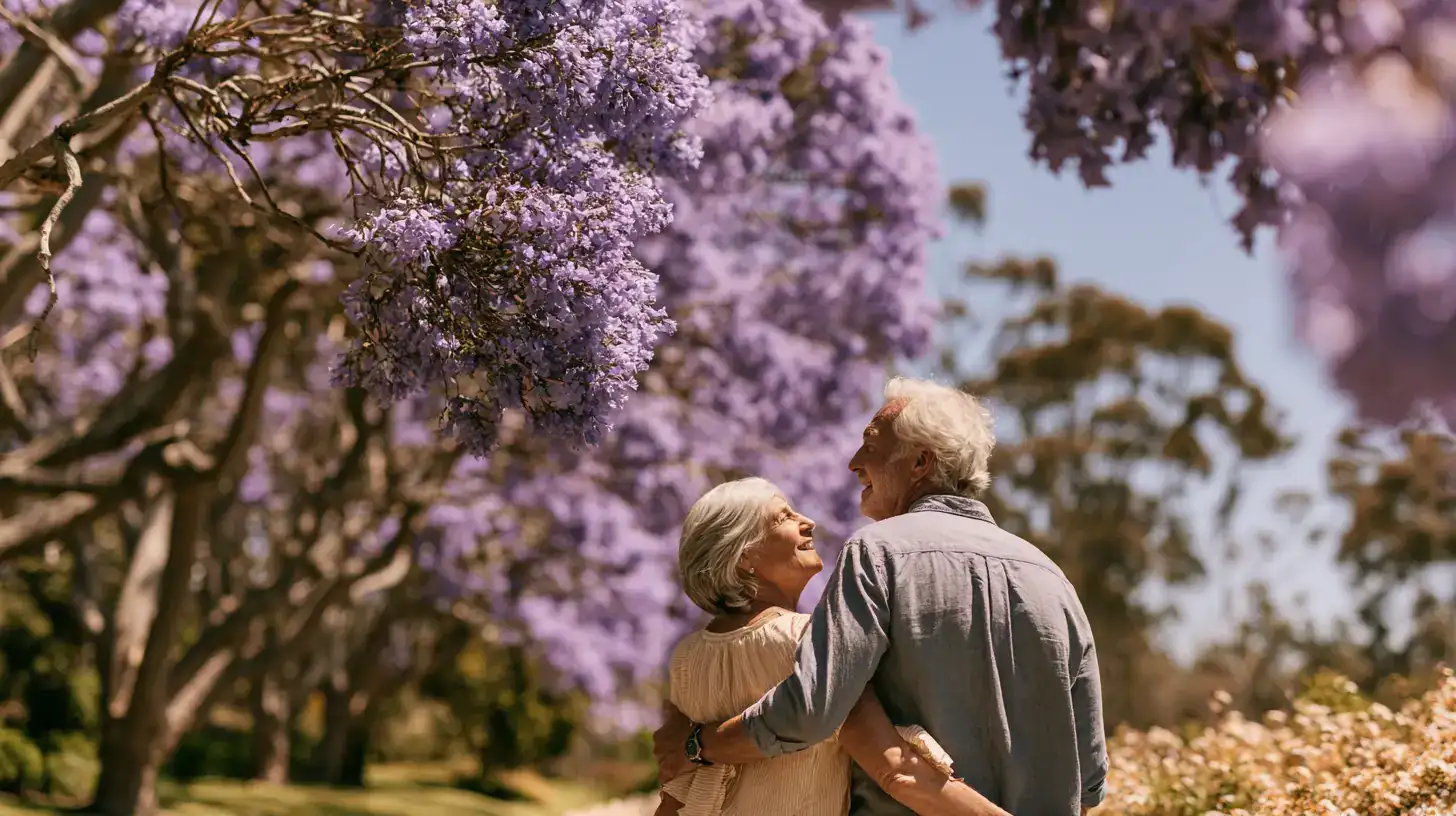 A white woman in her seventies and her adult son walking arm in arm past jacaranda trees