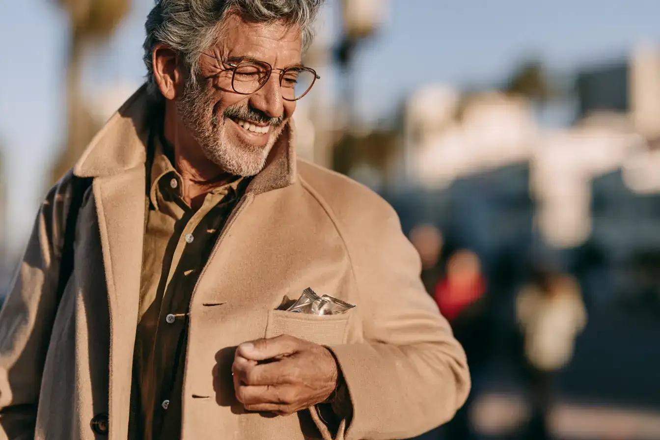 A Latino man in his seventies slipping a fresh pack of chewing gum into a coat pocket