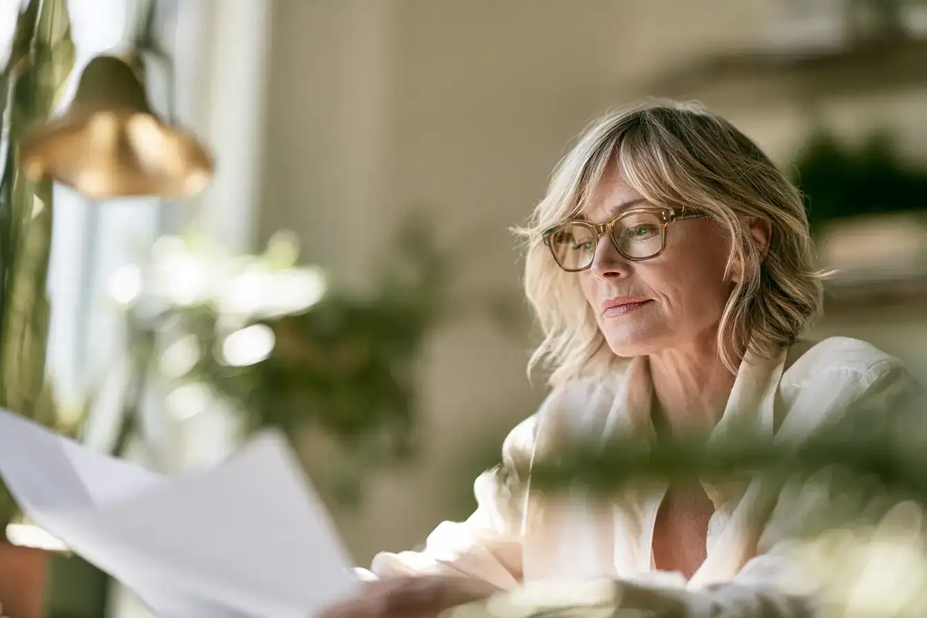 A white woman in her fifties switching off a bedside lamp, book face down