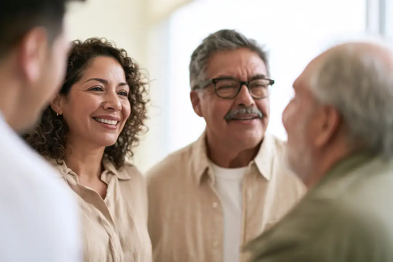 A Latina woman in her fifties and her father in his seventies laughing at something a grandchild just whispered