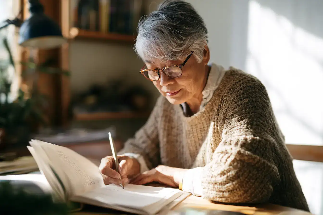 An Asian woman in her seventies stretching by an open window at first light
